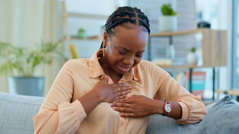 Black woman, chest pain and heart attack with health at home, emergency and breathing issue with indigestion. Respiratory, pneumonia or tuberculosis, lungs or cardiovascular healthcare or anxiety